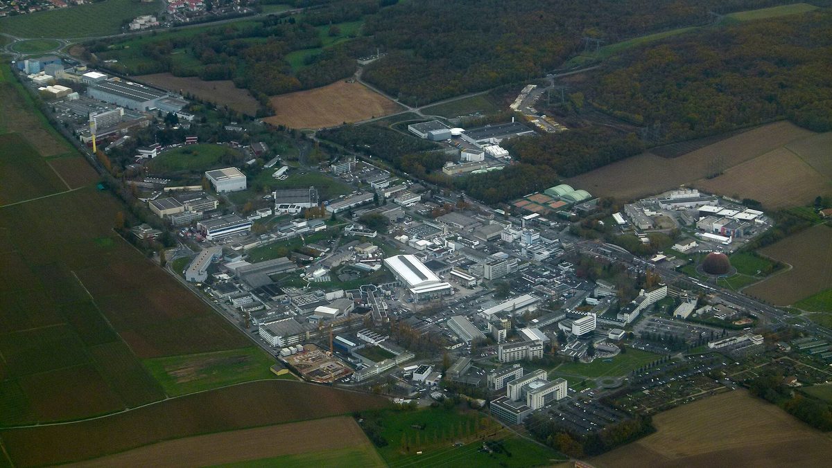 Aerial view of CERN's main site near Geneva: low lab buildings, parking lots and roads set among farm fields and woods