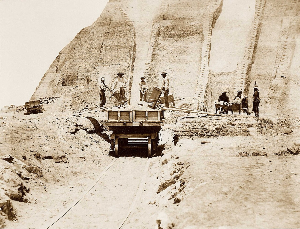 Workers loading guano into a rail cart at the foot of a huge pale heap, Chincha Islands, Peru, 1865
