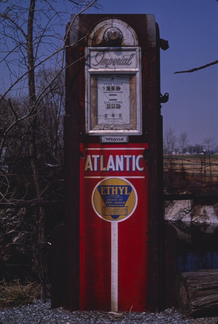 A rusted red Atlantic gasoline pump with a yellow and blue Ethyl anti-knock compound emblem